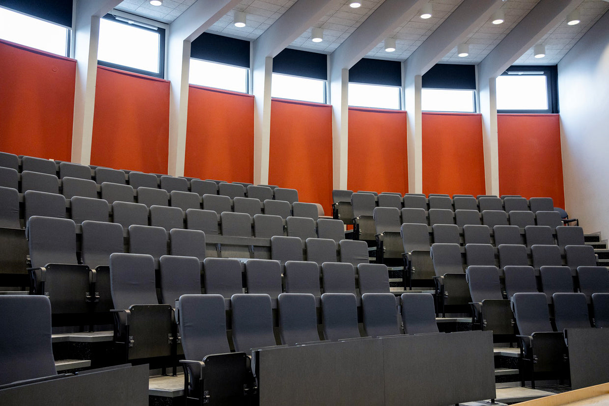 Nouseva penkkiriveistä auditoriossa, jossa punainen takaseinä.